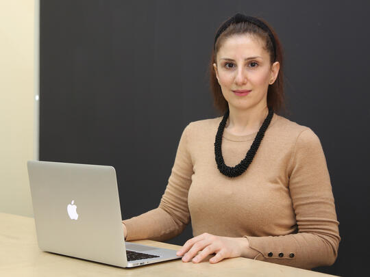 A women coder sitting on her desk in fron of her laptop