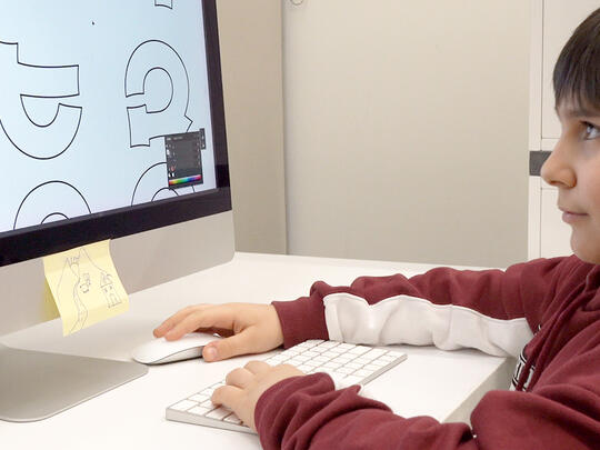 A kid coloring the Armenian Alphabet on a pc